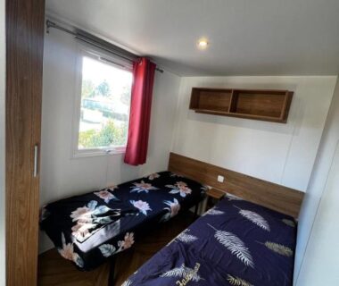 Chambre avec deux lits armoire et fenêtre dans le mobil home Lac des rêves