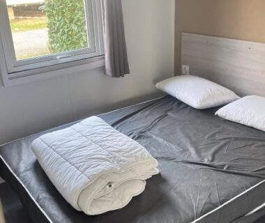 Chambre avec lit double et fenêtre au camping Lambé