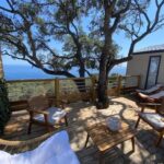 Terrasse en bois avec salon extérieur et vue mer au camping L'arbre perché