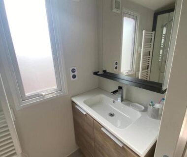 Salle d'eau avec lavabo miroir et fenêtre au camping L'arbre perché