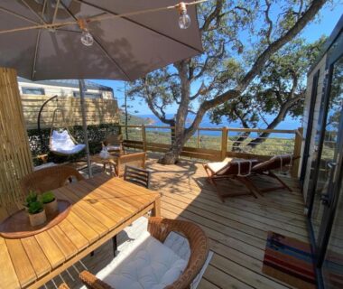 Terrasse en bois avec parasol fauteuils et vue mer au camping L'arbre perché