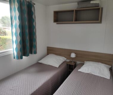 Chambre avec deux lits et lampe dans le mobilhome Le 384