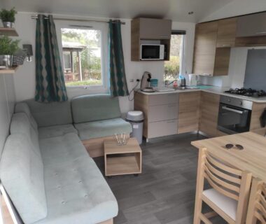 Intérieur de mobilhome avec canapé kitchenette et table du mobilhome Le 384 mobilhome Clim Velos TV lavlinge plancha transats