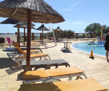 Bord de piscine avec transats et parasols au mobilhome Le 384 mobilhome Clim Velos TV lavlinge plancha transats