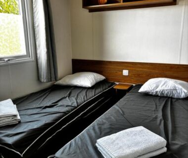 Chambre avec deux lits simples et serviettes au camping Le Bel' Azur