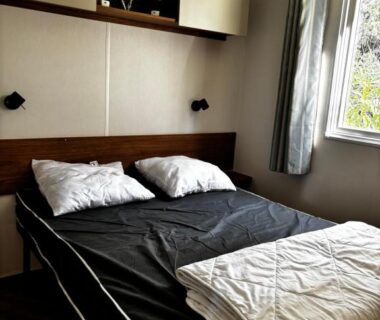 Chambre avec lit double et fenêtre sur verdure dans le mobilhome Le Bel' Azur
