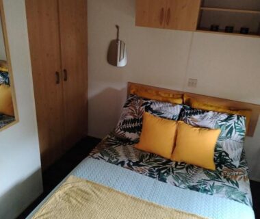 Chambre avec lit double coussins jaunes et placard au camping Le Bruant des Roseaux