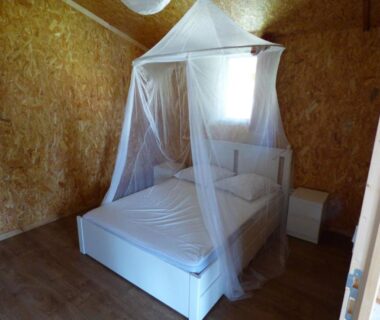 Intérieur de cabane en bois avec lit et moustiquaire dans Le Carbet Vendéen