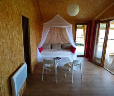 Intérieur de cabine avec banquette à baldaquin et table dans Le Carbet Vendéen