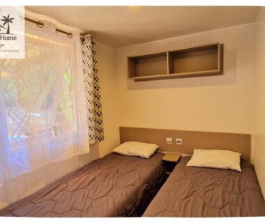 Chambre avec deux lits simples et fenêtre dans le mobil-home Le Casita des Eucalyptus