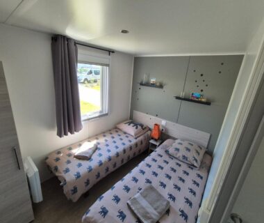 Chambre avec deux lits et fenêtre dans le mobile-home Le Chevreuil Vert