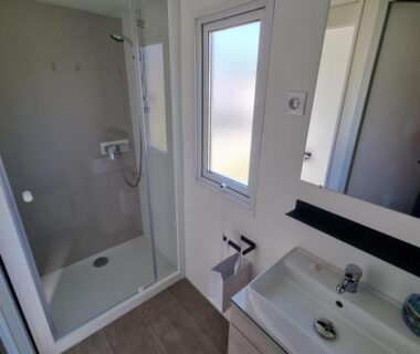 Salle de bain avec cabine de douche et lavabo dans le camping Le Chevreuil Vert