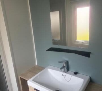 Salle de bains avec lavabo miroir et fenêtre du camping Le Clarys