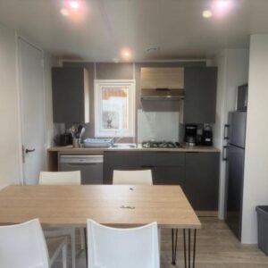 Cuisine équipée avec table et chaises dans le mobil home du camping Le Clarys