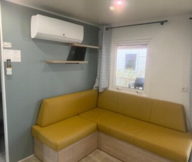 Coin salon avec banquette et climatisation dans l'hébergement du camping Le Clarys