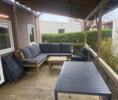 Terrasse couverte avec salon extérieur et table au camping Le Clarys