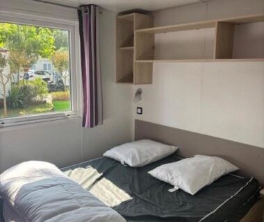 Chambre de mobil-home avec lit double et fenêtre au camping Le Cocon Landais