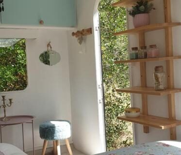 Chambre intérieure avec lit à couverture fleurie et fenêtre donnant sur végétation dans l'hébergement Le Cocon au fil de soi