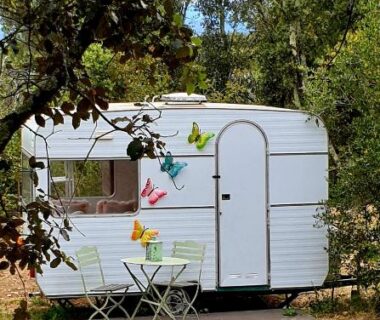 Devant une caravane blanche avec table et chaises au camping Le Cocon au fil de soi