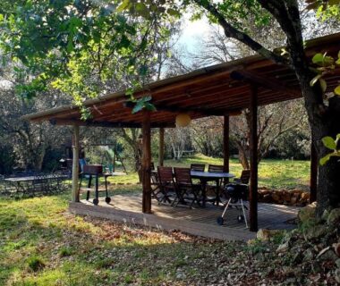 Terrasse ombragée avec table et chaises au camping Le Cocon au fil de soi