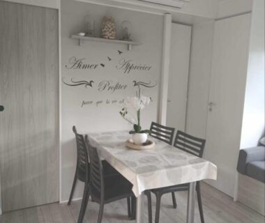 Intérieur mobil-home avec table et chaises et climatisation dans Le Cosy de Tess Mobil-home Sublima 6 personnes