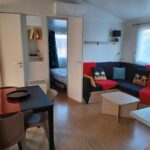 Séjour avec coin repas canapé et chambre visible dans le mobil-home Le Cosy