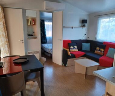 Séjour avec coin repas canapé et chambre visible dans le mobil-home Le Cosy