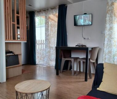 Séjour avec canapé et coin repas dans le mobil-home Le Cosy