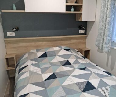 Chambre avec lit double et étagère décorative dans le mobilhome Le Cozy'Land Camping La Réserve