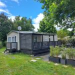 Mobilhome sur terrasse en bois dans jardin au Camping La Réserve Le Cozy'Land