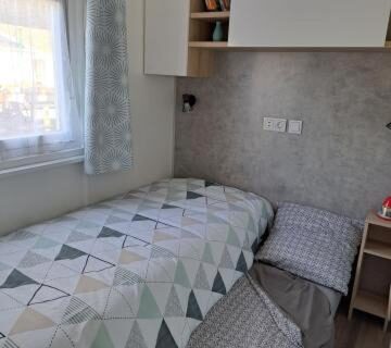 Intérieur du mobilhome avec lit simple et fenêtre dans Le Cozy'Land Mobilhome Camping La Réserve