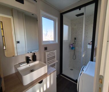 Salle de bain avec douche lavabo et lave-linge au Domaine des Pins