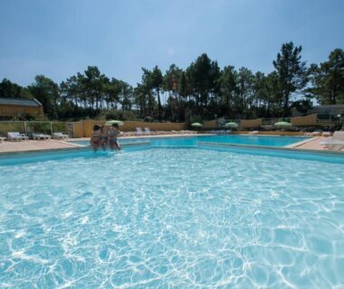 Piscine extérieure et transats au camping Le Domaine des Pins