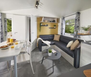 Salon avec canapé et coin repas dans le mobil-home du Domaine du Bois Coquet