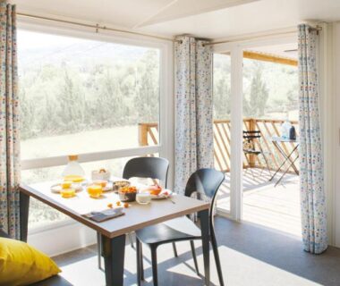 Salle à manger avec table dressée et terrasse ouverte au camping Le Goh Velin