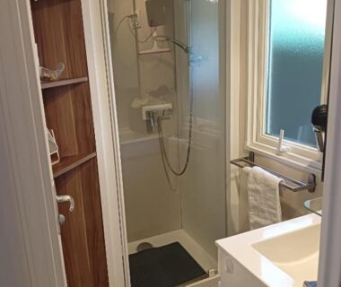 Salle de bain avec cabine de douche et fenêtre au camping Le HAVRE DU MEN DU