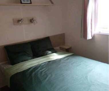 Chambre avec lit double et couette verte dans le camping Le Kraken