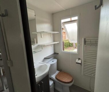 Salle de bains avec WC lavabo et étagères au camping Le Lac des Rêves