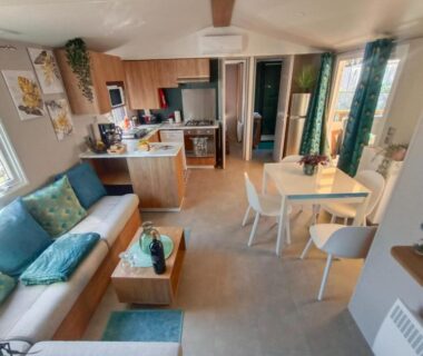 Séjour avec coin cuisine et canapé dans le bungalow Le Lagon Rose Camping SIBLU le Mar Estang