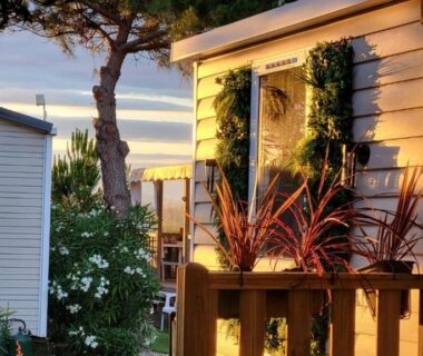 Façade et terrasse en bois éclairées au coucher du soleil au Lagon Rose Camping SIBLU le Mar Estang Canet-en-Roussillon