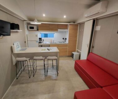 Intérieur mobilhome avec cuisine comptoir et canapé rouge du Mobilhome Douillet climatisé 5 pers en camping