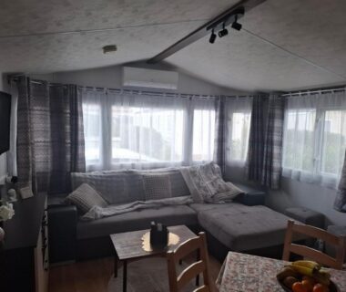 Séjour avec canapé d'angle et baie vitrée dans le mobilhome Le Montourey mobihome