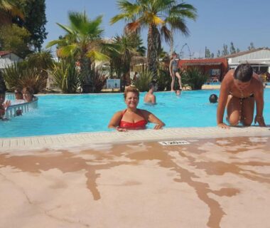 Piscine extérieure avec baigneurs et palmiers au camping Le Montourey mobihome