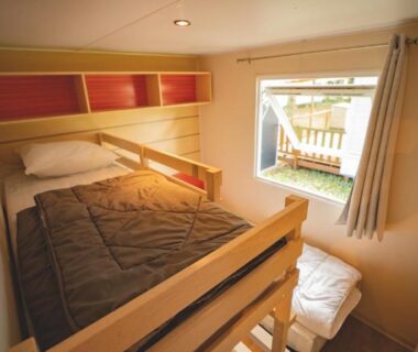 Chambre de mobil-home avec lit principal et lit superposé au camping Le Muscat