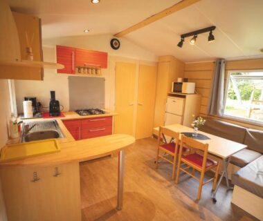 Intérieur de mobil-home avec kitchenette et coin repas au camping Le Muscat