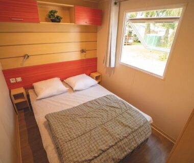 Chambre avec lit double et fenêtre donnant sur le camping Le Muscat
