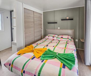 Chambre avec lit double et serviettes décorées au camping Le Nocia