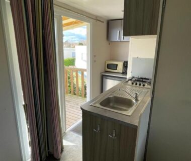 Coin cuisine et terrasse visible depuis l'intérieur dans le mobil-home Le Pont Rouge et Les Vignes