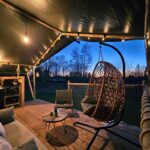 Terrasse sous toile avec fauteuil suspendu au Ranch Camping et Glamping
