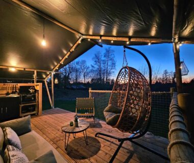 Terrasse sous toile avec fauteuil suspendu au Ranch Camping et Glamping